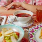 Stół z talerzem chłodnika, sałatką i napojami w bliskim kadrze