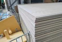 Jak tanio i skutecznie kupować materiały budowlane w Legionowie i Jabłonnie: praktyczny poradnik dla inwestora Stosy płyt gipsowo-kartonowych w magazynie materiałów budowlanych