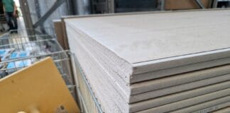 Jak tanio i skutecznie kupować materiały budowlane w Legionowie i Jabłonnie: praktyczny poradnik dla inwestora Stosy płyt gipsowo-kartonowych w magazynie materiałów budowlanych