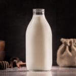 Szklana butelka na mleko na rustykalnym blacie w miękkim świetle