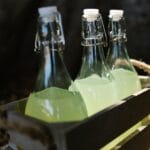 Szklane butelki z lemoniadą w drewnianej skrzynce, zbliżenie