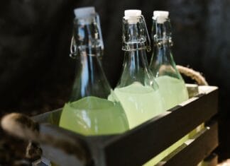 Szklane butelki z lemoniadą w drewnianej skrzynce, zbliżenie