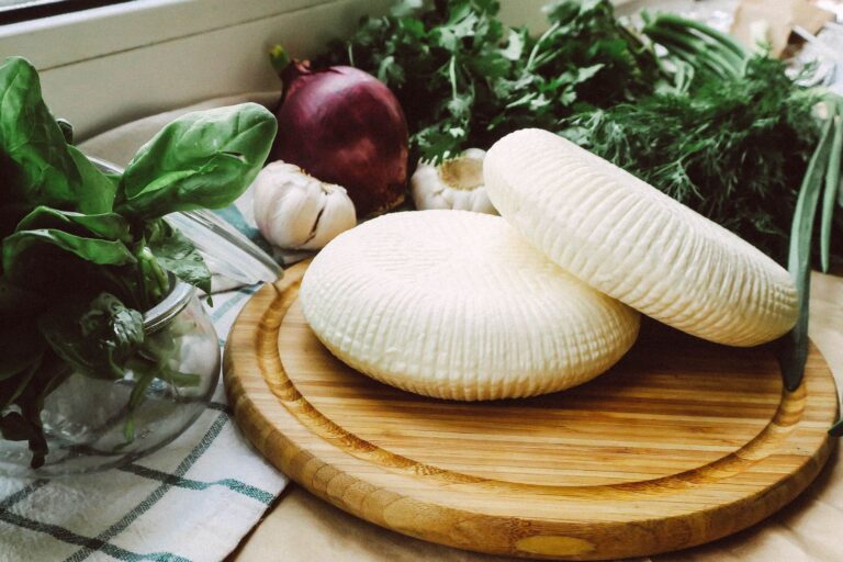 Świeża ricotta na drewnianej desce z bazylią, cebulą i czosnkiem